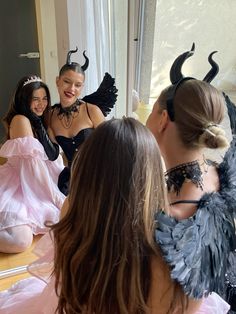 three women dressed up in costumes are sitting at a table and talking to each other