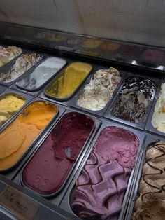 an assortment of ice creams in trays with different colors and flavors on display