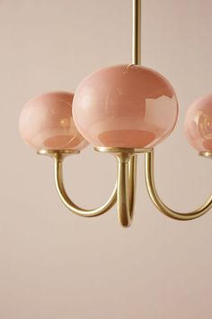 three pink glass balls hanging from a brass chandelier