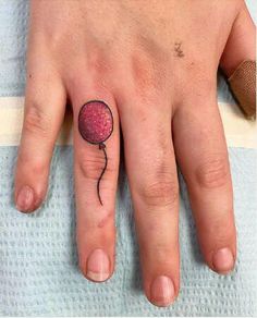 a person's hand with a small tattoo on it and a pink flower in the middle