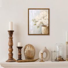 a white mantle with candles, vases and other items on it in front of a painting