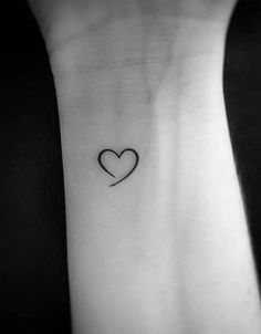 a heart tattoo on the wrist with a small black line in the shape of a heart