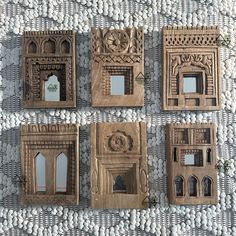 four carved wooden frames sitting on top of a white table covered in rocks and pebbles