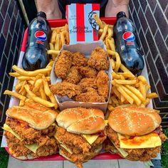 chicken sandwiches, fries and sodas are on a table with two bottles of pepsi