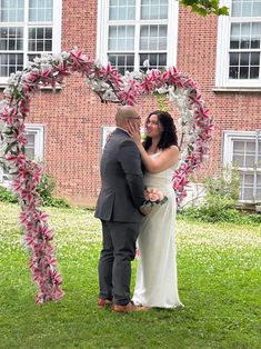 a man and woman standing next to each other in front of a heart shaped frame