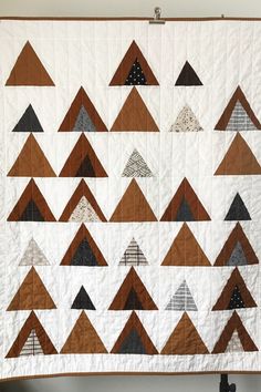 a quilted wall hanging with brown and white triangles