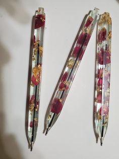 three pens sitting on top of a table next to each other with gold and red designs