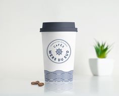 a coffee cup sitting on top of a table next to a potted plant