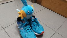 a stuffed animal sitting on top of a pair of blue tennis shoes in front of a door