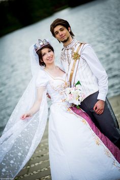 a man and woman dressed in wedding attire standing next to each other near the water