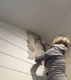 a woman is painting a wall with white paint and she has her hands on the board