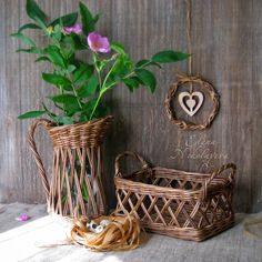 two wicker vases with flowers in them on a table next to some twine baskets