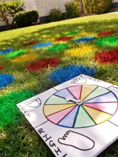 a white board with a rainbow wheel on it sitting in the middle of some grass