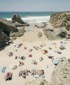 many people are laying on the beach with umbrellas and towels in front of them