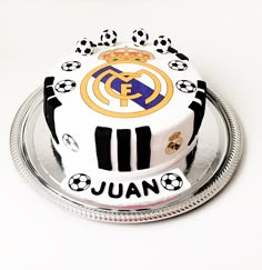 a cake decorated with soccer balls and the word juan on it is sitting on a silver platter