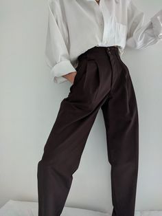 The Na Nin Townes Trousers are inspired by classic 90s style and can be worn in many ways throughout the seasons. Made with lightweight cotton, they are durable, yet allow for movement and feature a relaxed waistline that can be worn high or low on the waist. The thoughtful details of these trousers include pockets, belt loops, cuffs and double pleats. For an elegant classic look, pair with our Fiona Top in cotton poplin and your favorite gold pieces from our In House Jewelry Line. Made In USA Chic Baggy Bottoms For Everyday Wear, Modern Cotton Bottoms For Daywear, Modern Cotton Pants For Fall, Chic Everyday Brown Bottoms, Chic Brown Bottoms For Everyday Wear, Classic Baggy Bottoms For Everyday, Classic Baggy Bottoms For Spring, Chic Brown Cotton Pants, Classic Baggy Pants For Fall