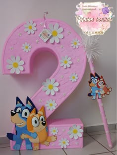 a pink number two with cartoon characters on it and flowers in the corner next to it