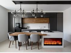 a modern kitchen with an electric fireplace in the center and dining table next to it