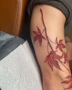 a woman's arm with red leaves on it