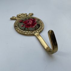 a gold hook with a red rose on it and an ornate design in the middle