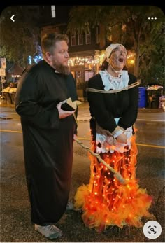 two people dressed in costumes standing next to each other on the street at night time