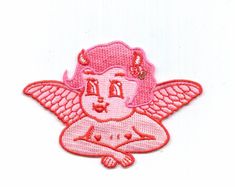 an embroidered patch with a pink angel sitting on it's chest and arms crossed