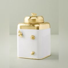 a white and gold canister sitting on top of a table