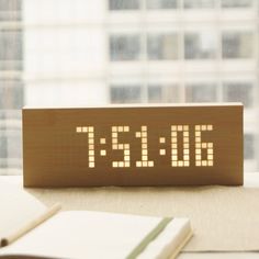 an electronic clock sitting on top of a table next to a book and some books