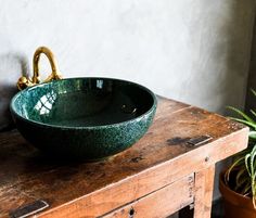 a green bowl sitting on top of a wooden table next to a potted plant