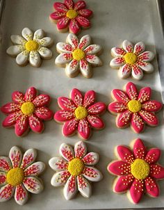 decorated cookies in the shape of flowers on a baking sheet