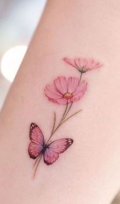 a small pink flower with a butterfly on it's side ribcage tattoo