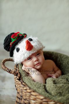 a baby wearing a knitted snowman hat in a basket