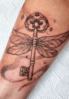 a dragonfly tattoo with a key on it's arm