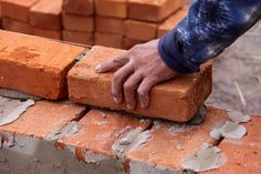 a man is placing bricks into a brick wall