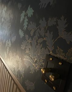 the wall is decorated with gold and silver leaves on it, along with a stair case