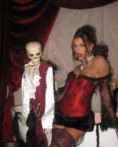 a woman in a red corset posing next to a skeleton