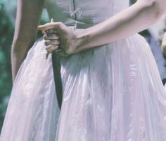 a woman in a white dress is holding a black tie and wearing a pink dress