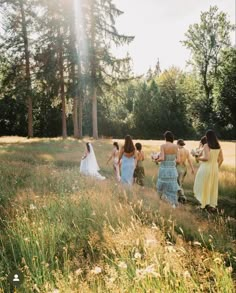 a group of women in dresses walking through a field