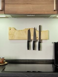 three knives are hanging on the wall next to a microwave