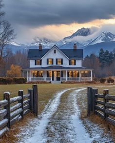 a large white house sitting on top of a lush green field next to a snow covered mountain