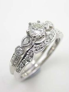 a white gold engagement ring with an intricate design on the band and center stone set