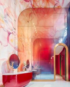 a bathroom with a red tub and colorful wallpaper on the walls, along with a mirror