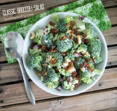 a white bowl filled with broccoli salad on top of a wooden table