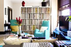 a living room filled with lots of furniture and bookshelves full of records on shelves