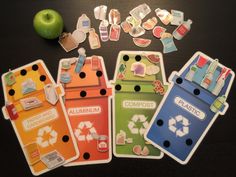 an assortment of stickers and magnets sitting on a table next to an apple