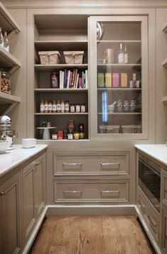 a kitchen with white cabinets and lots of counter space in the center, along with an open pantry door