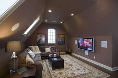 an attic living room with couches and a flat screen tv on the wall in it