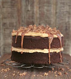 a chocolate cake with caramel icing and nuts on top sitting on a wire rack