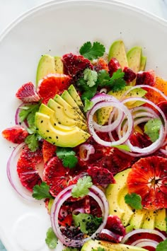 a white plate topped with fruit and veggies next to sliced avocado