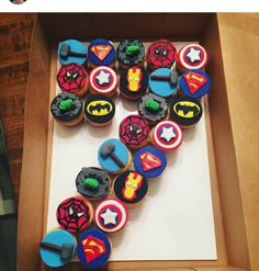 a box filled with cupcakes covered in icing and decorated like superheros